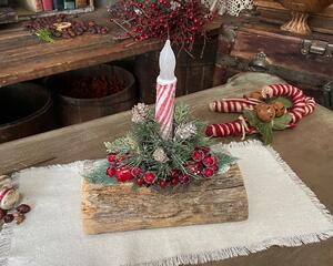 This is a yule log centerpiece with a snowy pine and red berry arrangement. It holds a battery-operated candy cane candle. 